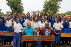 Lalji foundation leader and Kasulu students with new wooden school desks