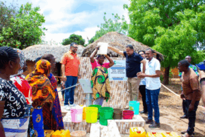 Lalji-foundation-chairman-helping-a-woman carry a bucket of water at mabana shallow well