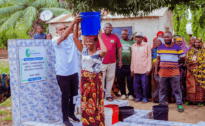 Lalji foundation representative helping a woman carry a bucket of clean and safe water