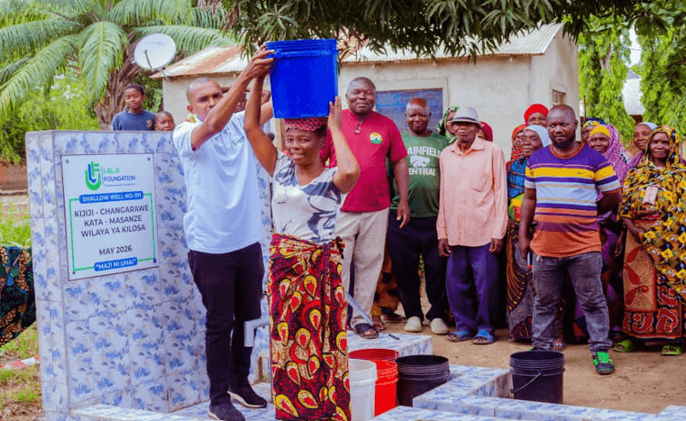 Lalji foundation representative helping a woman carry a bucket of clean and safe water